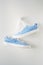 Pair of blue striped female sneakers hanging on a white background