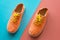 Pair of bright orange sneakers on colorful bicolor background, closeup
