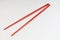 A pair of bright red melamine chopsticks on white background