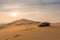 A pair of brown flip flops in the desert at sunset