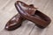 Pair of Brown Stylish Leather Penny Loafer Shoes Placed On Mesh Surface.