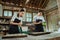 A pair of cake makers wearing aprons are kneading the dough in a bowl while baking a cake