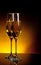 A pair of champagne flutes on table on dark golden light background