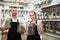 Pair of charming sellers with aprons at store of herbs and ecological food