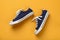 Pair of classic blue sneakers or gumshoes with white shoe laces on a textured yellow background. Comfortable shoes for fitness and