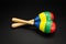 A pair of colorful maracas lying on a black underground