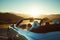 pair in a convertible, parked with sun beaming down