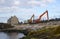 A pair of cranes ready to dredge the small harbor at Ballintoy on the North Antrim Coast of Northern Ireland on a calm spring day.