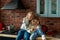 Pair of cute adorable caucasian blond siblings boy and girl wear sweater and jeans enjoy have fun sitting on kitchen