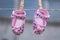 Pair of cute, pink-colored baby shoes with brown dots hanging from the wire with wooden clothespins