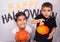 Pair of cute siblings posing near a spooky Halloween-themed background