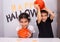 Pair of cute siblings posing near a spooky Halloween-themed background