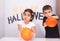 Pair of cute siblings posing near a spooky Halloween-themed background