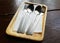 Pair of cutlery silverware spoon fork on rectangle  serving wooden tray on dark brown table at fresh market gourmet restaurant