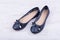 Pair of dark blue ladies` flat shoes on white wooden background