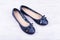 Pair of dark blue ladies` flat shoes on white wooden background
