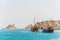 a pair of dhows - traditional arab ships - is heading to the sea from Muttrah part of Muscat dominated by a fort on a