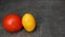 Pair of different tomatoes on a gray stone background. Yellow oblong and red round tomatoes.