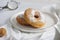 A pair of donuts in a plate on a gray table.