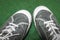 Pair of Dusty Gray Leather Gumshoes Sneakers with White Laces and Soles on Green Background. Top-Down View. Active People Concept