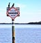 A pair of egrets on a boat warning sign in the channels approach