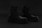 Pair of elegant isolated autumn winter unisex black boots with black laces on bright black background. Boots with block