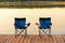 A pair of empty chairs stand on a wooden pier