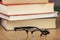 Pair of eyeglasses next to a pile of books