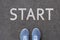 Pair of feet on tarmac road with print of word start for concept of starting point