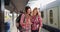 Pair of female backpackers navigating destination on phone at train station