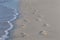 Pair of footprints in the sand at waters edge