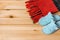 Pair of funny cat face blue slippers and red knit scarf with fringe over natural wood surface. Ð¡omfy soft fleece home shoes for
