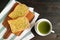 Pair of Garlic Butter Toasts on Breadboard with a Cup of Hot Green Tea on Wooden Table