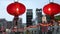 Pair of Glowing Light Red Asian Paper Lanterns Hanging with City Street in Background