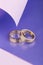 Pair of gold wedding rings on purple and pink background