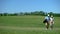 Pair of golfers with clubs bag communicating during course walk after game hobby