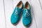 Pair of green casual suede shoes with laces on wooden background. Turquoise women`s oxfords, oxford shoe