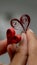 A pair of hands cradle a small, intricately crafted red paper heart