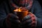 A pair of hands, enveloped in warm gloves, cradle a steaming cup, emitting a fiery glow against a cozy backdrop.