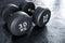 A pair of heavy 30 kilogram dumbbells on rubber floor matting at the gym. Made with cast iron and coated with rubber.