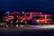 A pair of highly modern and quality fire trucks illuminate the night with their rotating lights, symbolizing the cutting