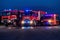 A pair of highly modern and quality fire trucks illuminate the night with their rotating lights, symbolizing the cutting