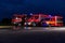 A pair of highly modern and quality fire trucks illuminate the night with their rotating lights, symbolizing the cutting