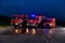 A pair of highly modern and quality fire trucks illuminate the night with their rotating lights, symbolizing the cutting