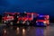 A pair of highly modern and quality fire trucks illuminate the night with their rotating lights, symbolizing the cutting