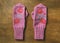 Pair of homemade woolen pink mittens for children on wooden back