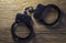 A pair of locked handcuffs without a key, lying on a textured wooden board with space to copy.