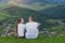 Pair of lovers sit on a hill and admire the view of the mountain