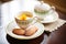 a pair of madeleines on a saucer with a frothy cappuccino