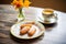 a pair of madeleines on a saucer with a frothy cappuccino
